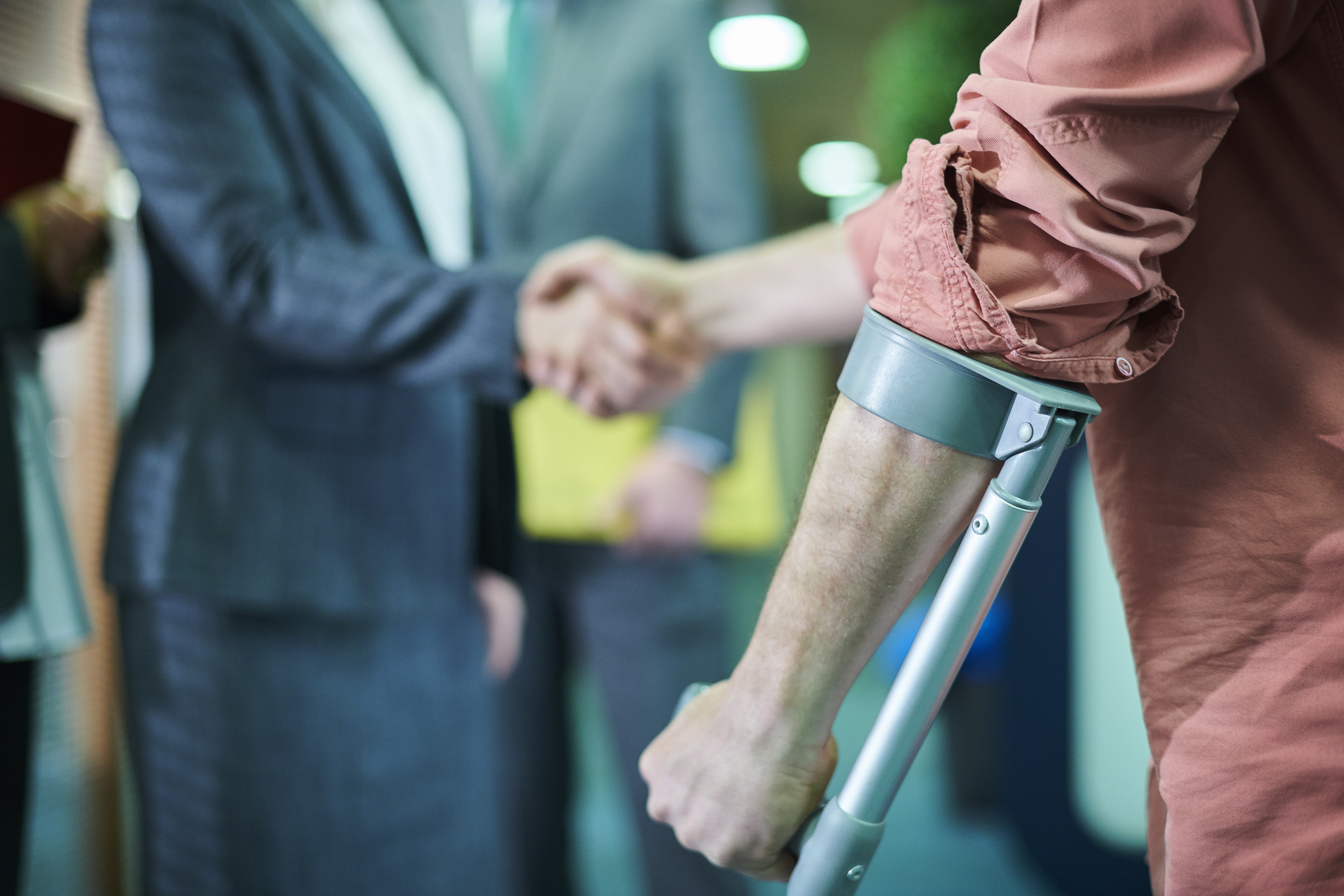 Two men shaking hands, one using a support